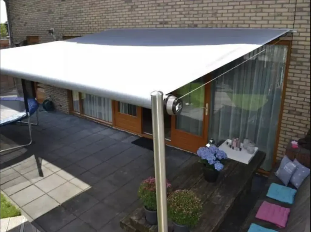 Freistehende Markise über einer Terrasse mit Sitzbereich an einem Wohnhaus